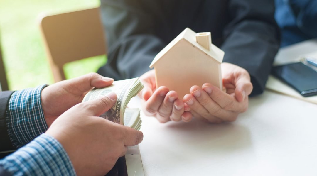 Professional handshake over real estate documents with cash transaction elements visible