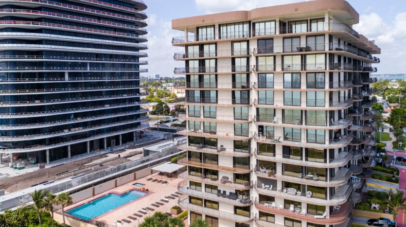 Exterior view of a Florida condo building with a pool and palm trees