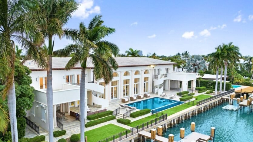 Luxurious waterfront mansion with pool and palm trees in Miami, South Florida, USA. Elegant architecture, scenic view.