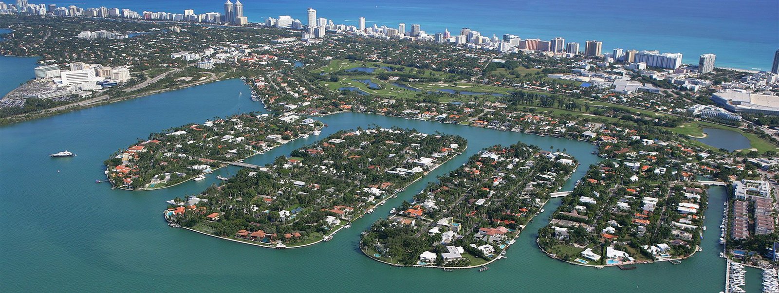 An aerial view of the exclusive Sunset Islands in Miami Beach, showing luxury homes and yachts docked at private piers