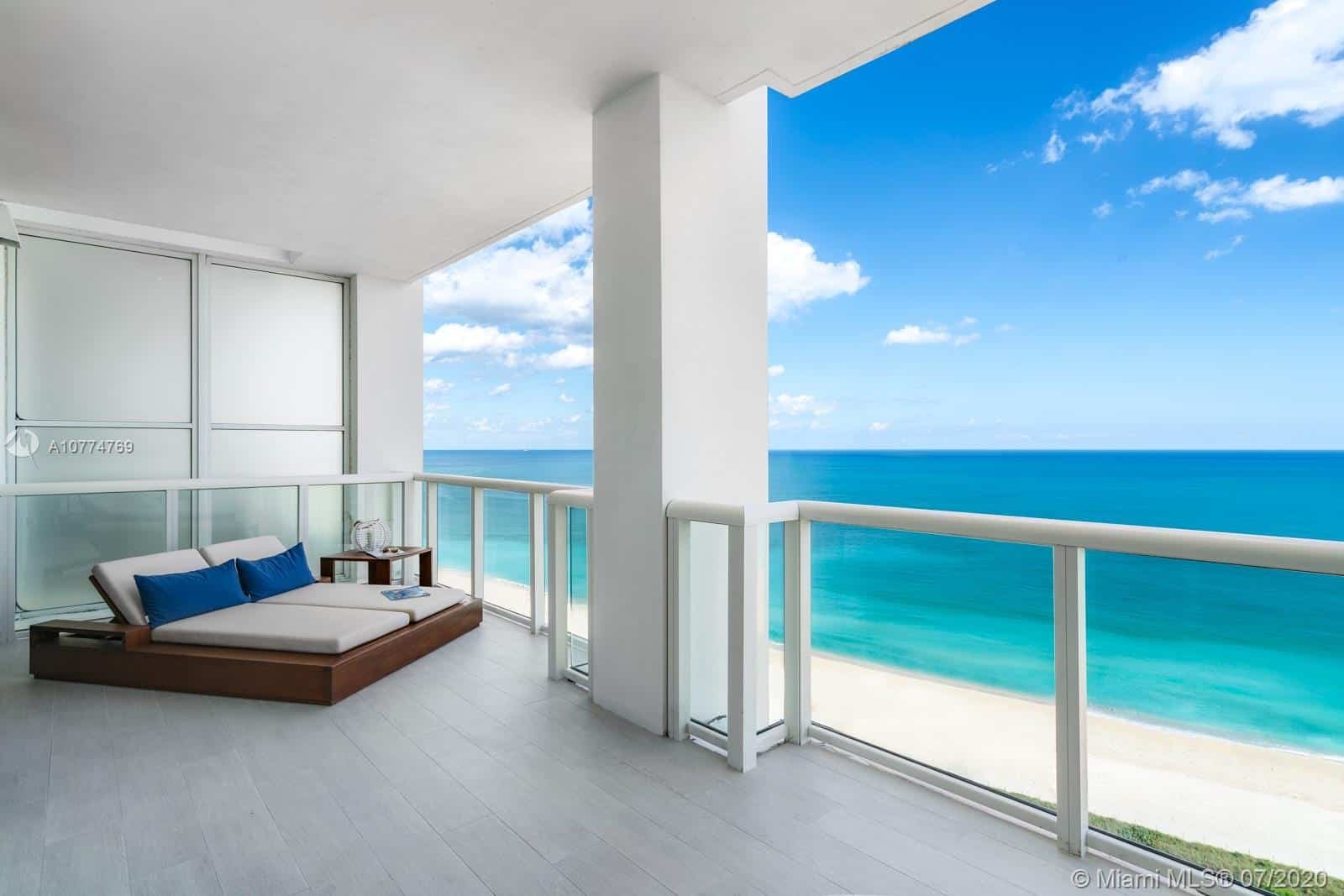 A stunning view from a luxury Miami condo overlooking the ocean at sunset, representing the high-end market