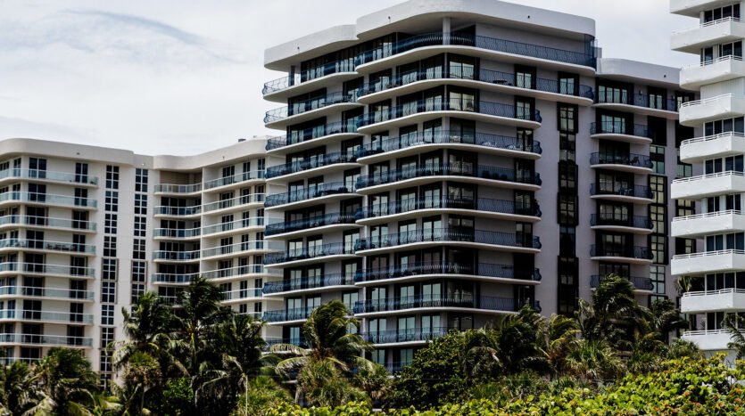 Beachfront condominiums with lush greenery in Miami, South Florida, USA. Person walking on sand in the foreground.