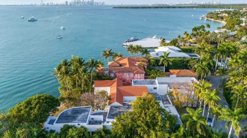 Aerial view of waterfront homes with lush greenery in Miami, Florida, USA, showcasing Biscayne Bay and the city skyline.