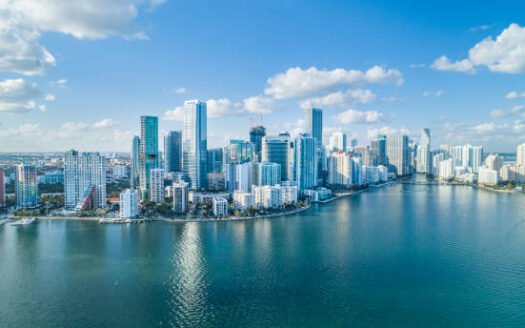 Aerial view of Miami skyline with skyscrapers along Biscayne Bay under a clear blue sky, South Florida, USA for our Miami Real Estate Market Repor