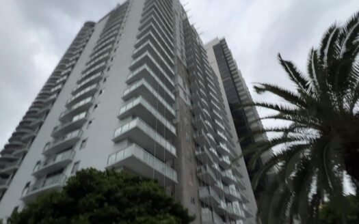 Tall apartment buildings under cloudy skies with palm trees; Miami, South Florida. Urban architecture, real estate. Article about Selling a condo with a Special Assessment in Miami