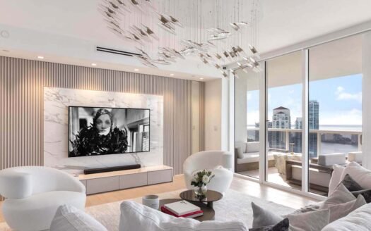 Pre-construction luxury condo. Modern Miami apartment living room with city view, sleek decor, large TV, artistic lighting, and balcony seating.